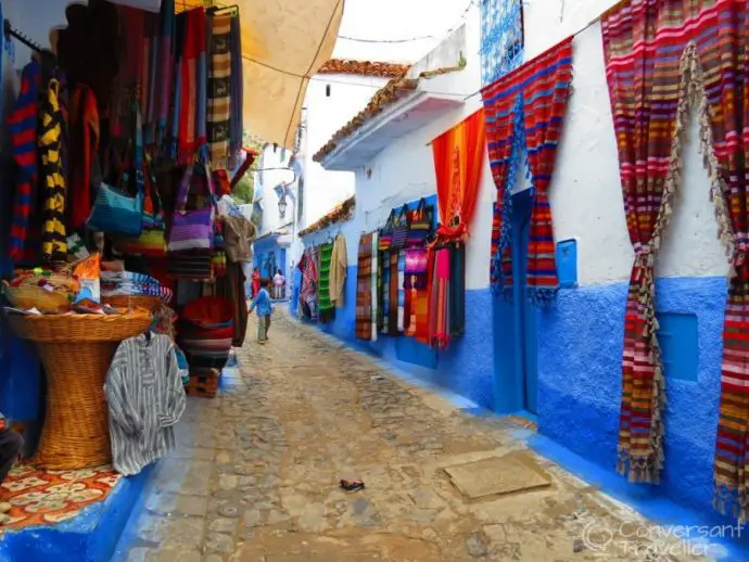 Blue and white houses with colourful souvenirs hanging up outside