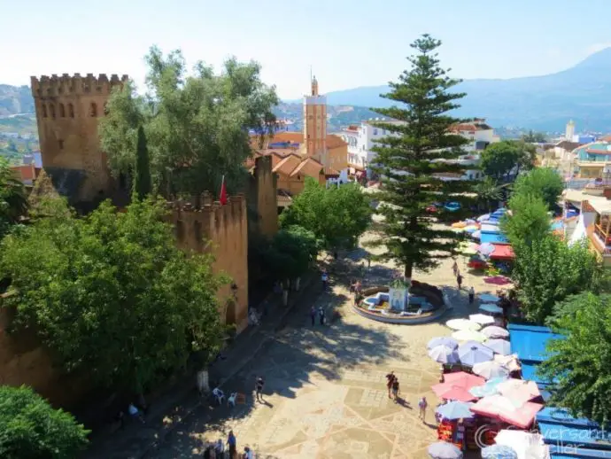 A quiet city square with old kasbah to the left and cafes to the right