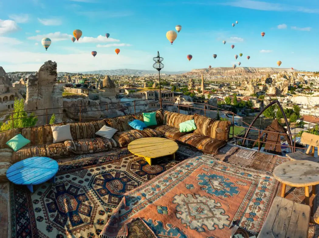 Terrace covered with rugs and hot air balloons in the distance