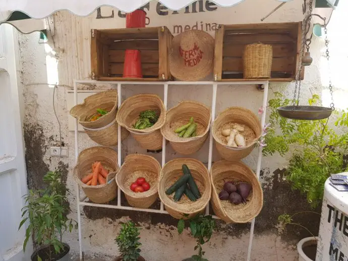 White vegetable rack on a wall with courgettes, carrots and tomatoes 