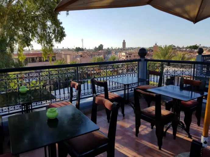 Roof terrace with tables and chairs overlooking the Marrakech city skyline
