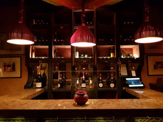 Bar with red ceiling lamps and bottles of wine behind the counter