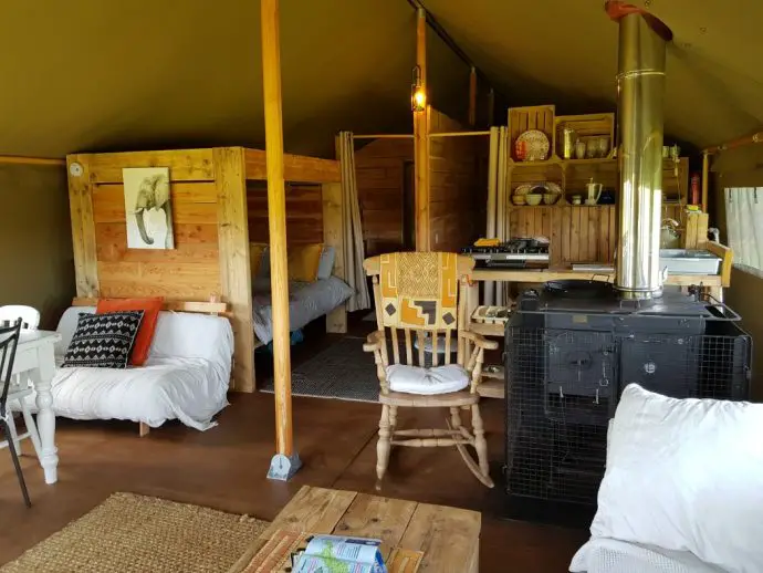 Living area inside the glamping tent with wood burner stove and rocking chair