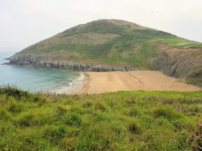 Beach cover will hill top in background and sea to the left