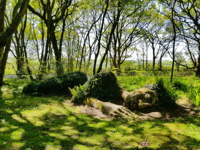 sculpture of a woman in a forest made out of mud