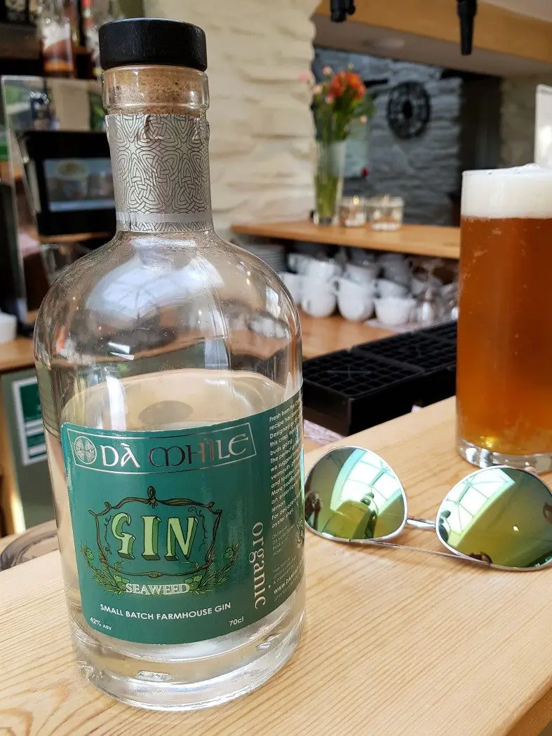 Bottle of seaweed gin on a bar next to a pair of sunglasses