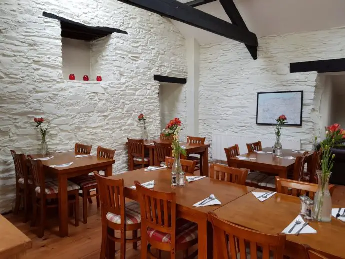 Cafe inside an old barn building, with whitewashed walls, wooden ceiling beams, and wooden tables