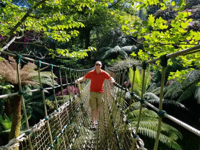 man walking across a rope bridge in a jungle