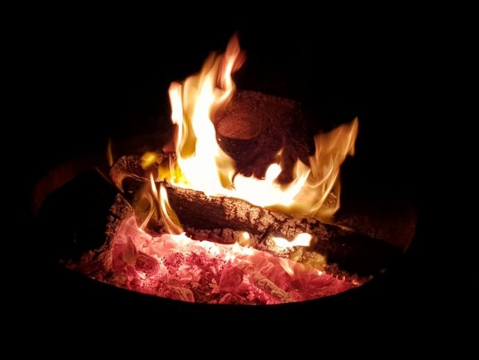 Fire pit with burning logs against a dark background