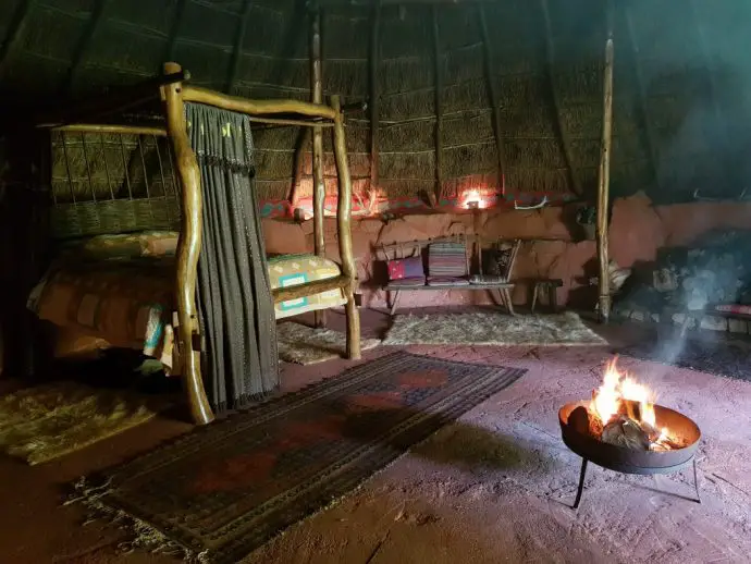 Inside an iron age roundhouse with wooden four poster bed and a fire pit - romantic places to stay in Cornwall