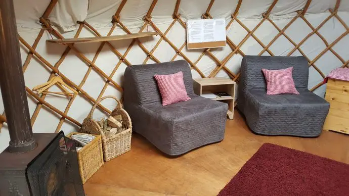 Interior of a yurt on a Lake District Glamping site with 2 chairs and a wood basket