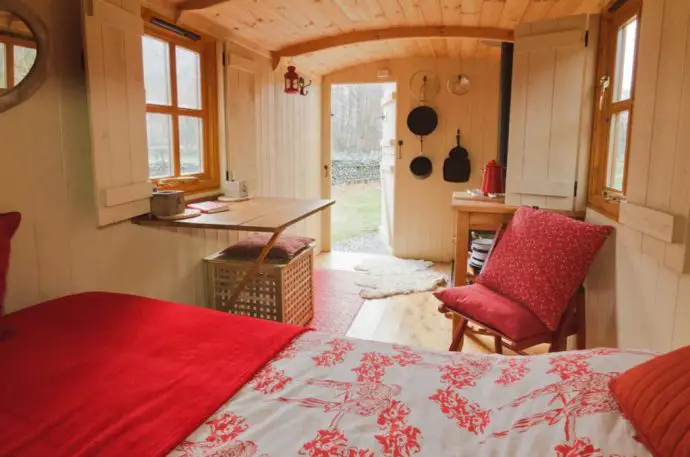 Red interior of a glamping hut with bed, chair and desk
