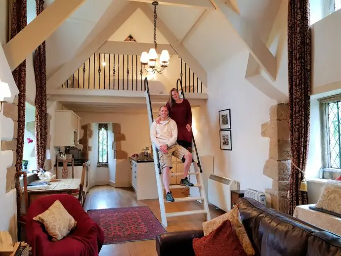 Living area with mezzanine gallery and ladder, with two people sitting on it