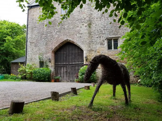 Willow horse sculpture in front of an old gatehouse