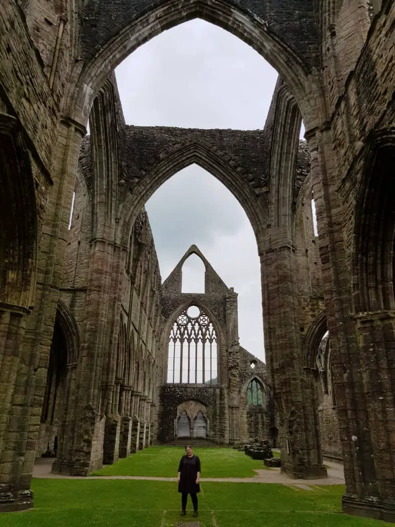 Inside a ruined abbey with big archways and a small person standing beneath