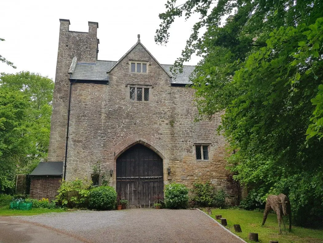 Medieval stone gatehouse with two towers and trees all around