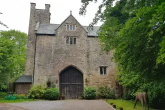 Medieval stone gatehouse with two towers and trees all around