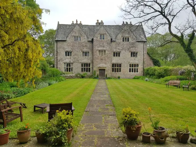 Old historic stone medieval manor at the opposite end of a large lawn