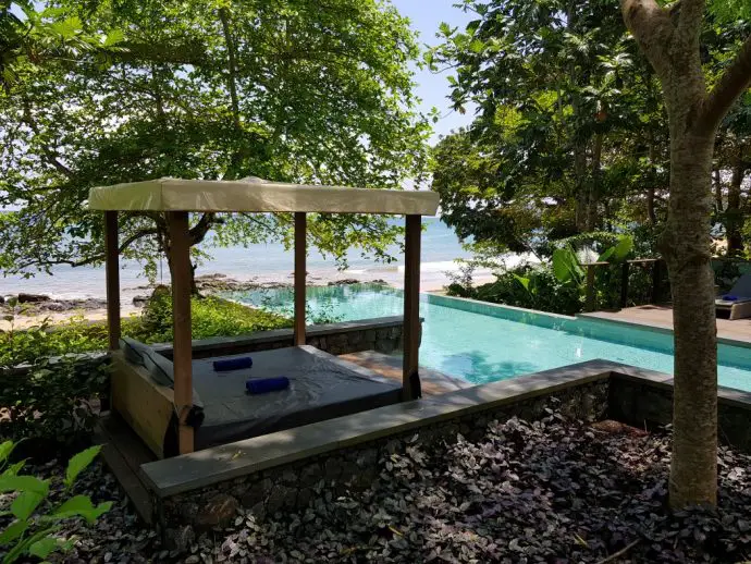 Infinity pool overlooking a beach with a sun lounger in the foreground