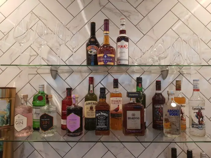 Drinks bottles including gin and whisky on glass wall shelving