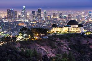 Domed art deco building lit up at night against a city backdrop.