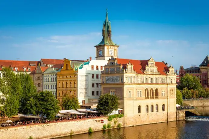 Medieval stone buildings with red roofs on the banks of a river