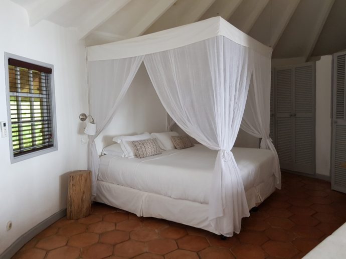 Four post bed with white bedding and white drapes