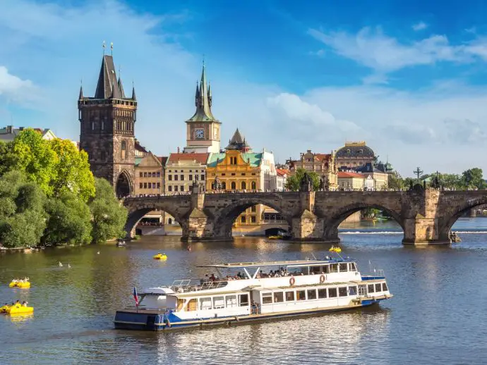 Boat cruiser on a river heading towards an arched stone bridge