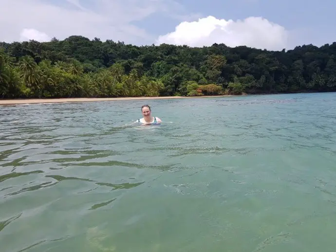 Woman swimming in sea with a backdrop of palm trees