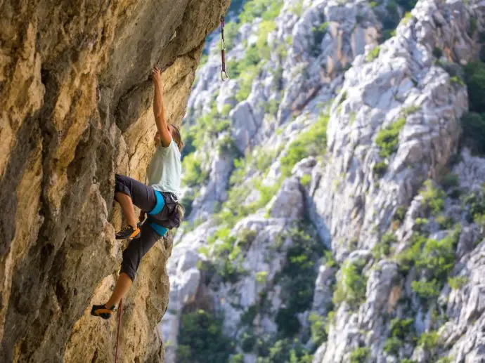 Man climbing on rock face with distant mountain in background