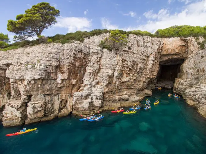 White cliffs and a sea cave with yellow and red kayaks near the entrance