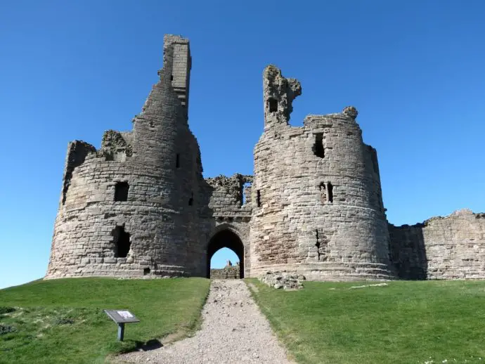 Ruined castle down on a green hill with blue sky