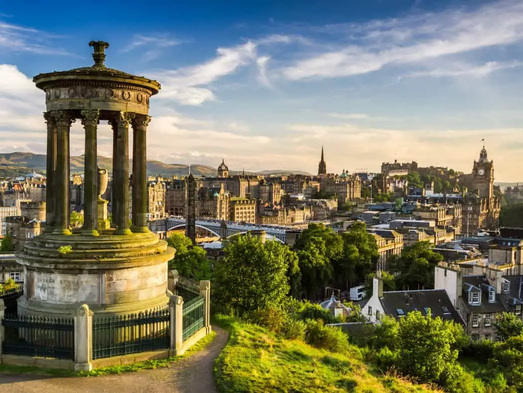 Edinburgh skyline with blue sky and a stone monument in the foreground