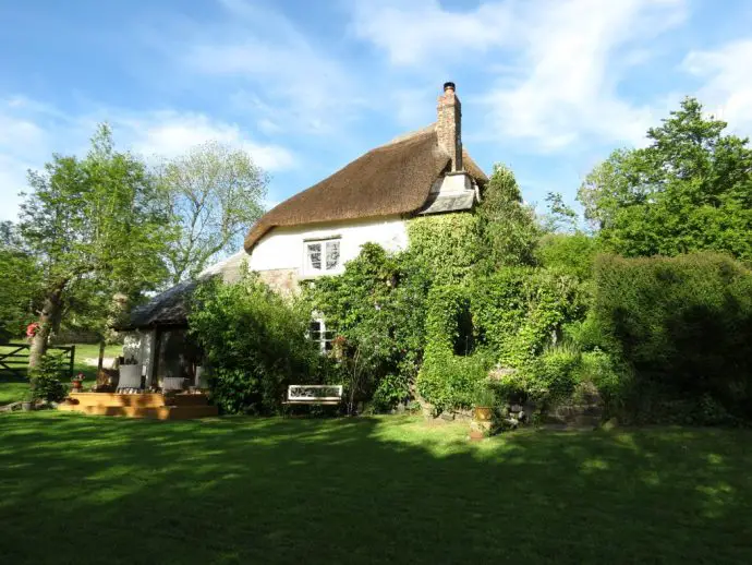 Thatched cottage surrounded by lush green garden