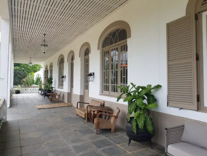 Wide stone balcony adjacent to white house with arched windows and plants - Review of a stay at Roça Sundy on Principe