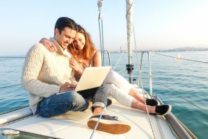 Couple working on laptop on sailling boat - digital nomad remote working