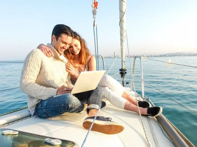 Couple working on laptop on sailling boat - digital nomad remote working