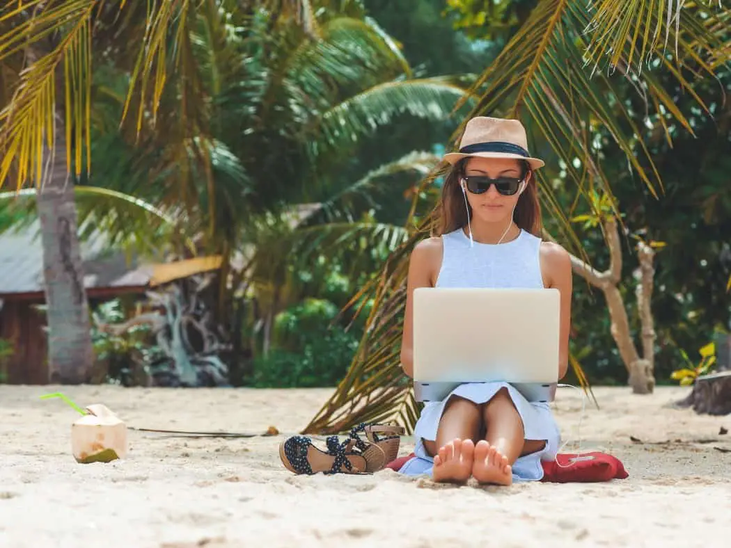 Digital Nomad - woman working with laptop on a beach - remote working