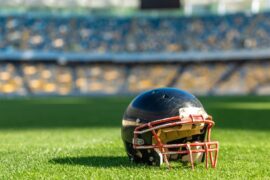 American football helmet on the green grass floor of a stadium