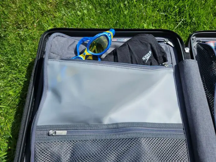 Open Level8 Voyager suitcase showing a waterproof pocket with googles and swim shorts inside.