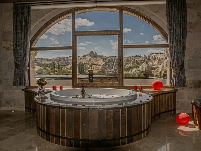 Bathroom with circular bath and a window overlooking a rocky valley