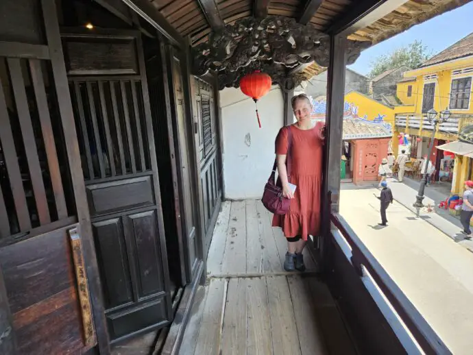 Woman in an orange dress standing on a wooden balcony