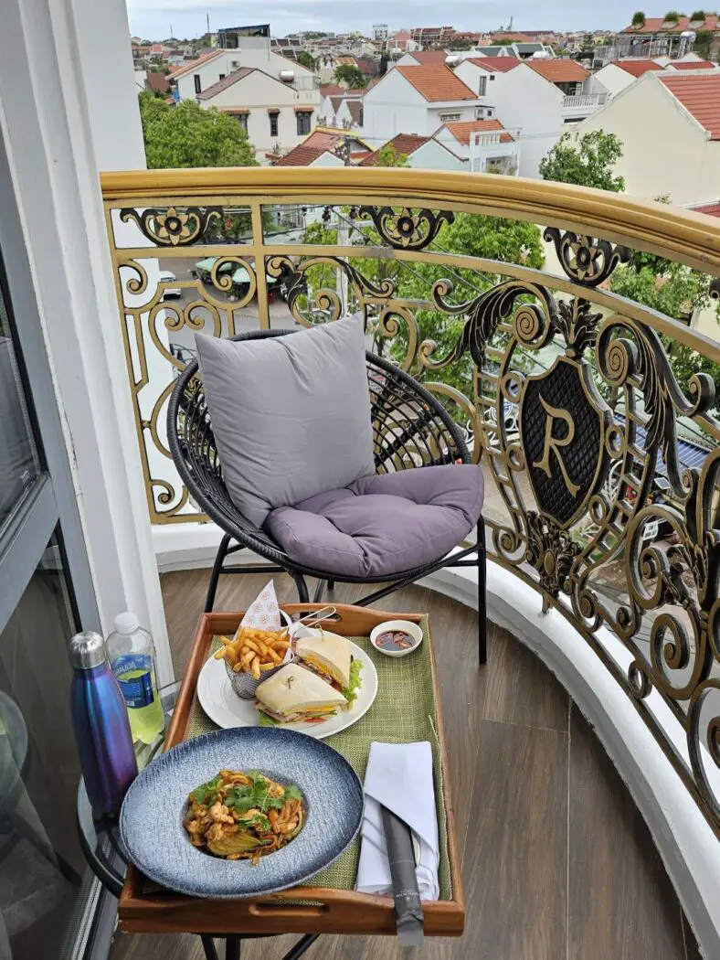 Balcony with a chair and table with plates of food on it