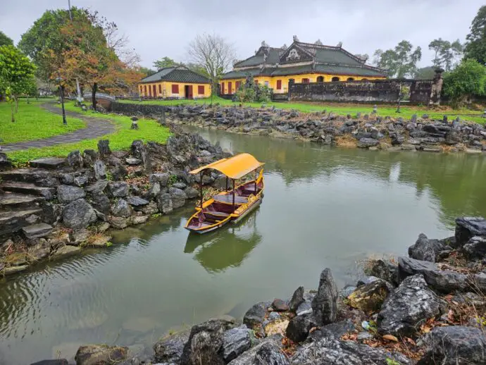 River with a small boat and a yellow palace building in the background